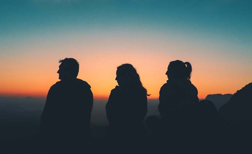 three traveling friends silhouetted in the sunrise