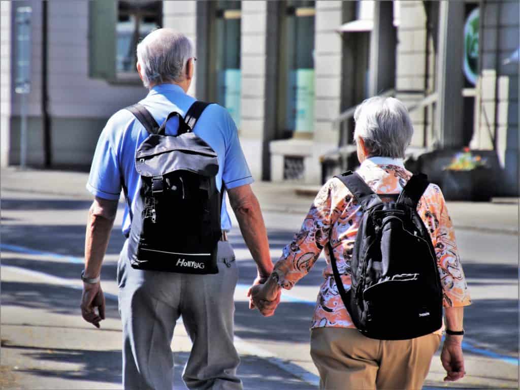 happy senior travelers holding hands