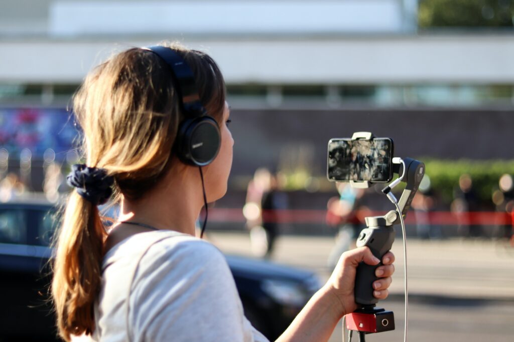 woman with headphones holding camera equipment
