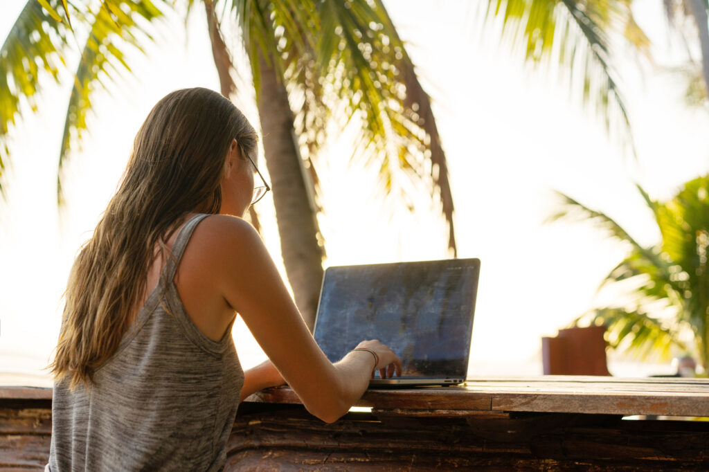 how to become a travel writer freelancer girl with a computer among tropical palm trees work on the island in sunset
