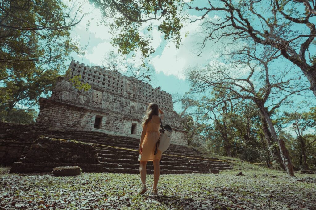 woman standing in front of mayan ruins mexico